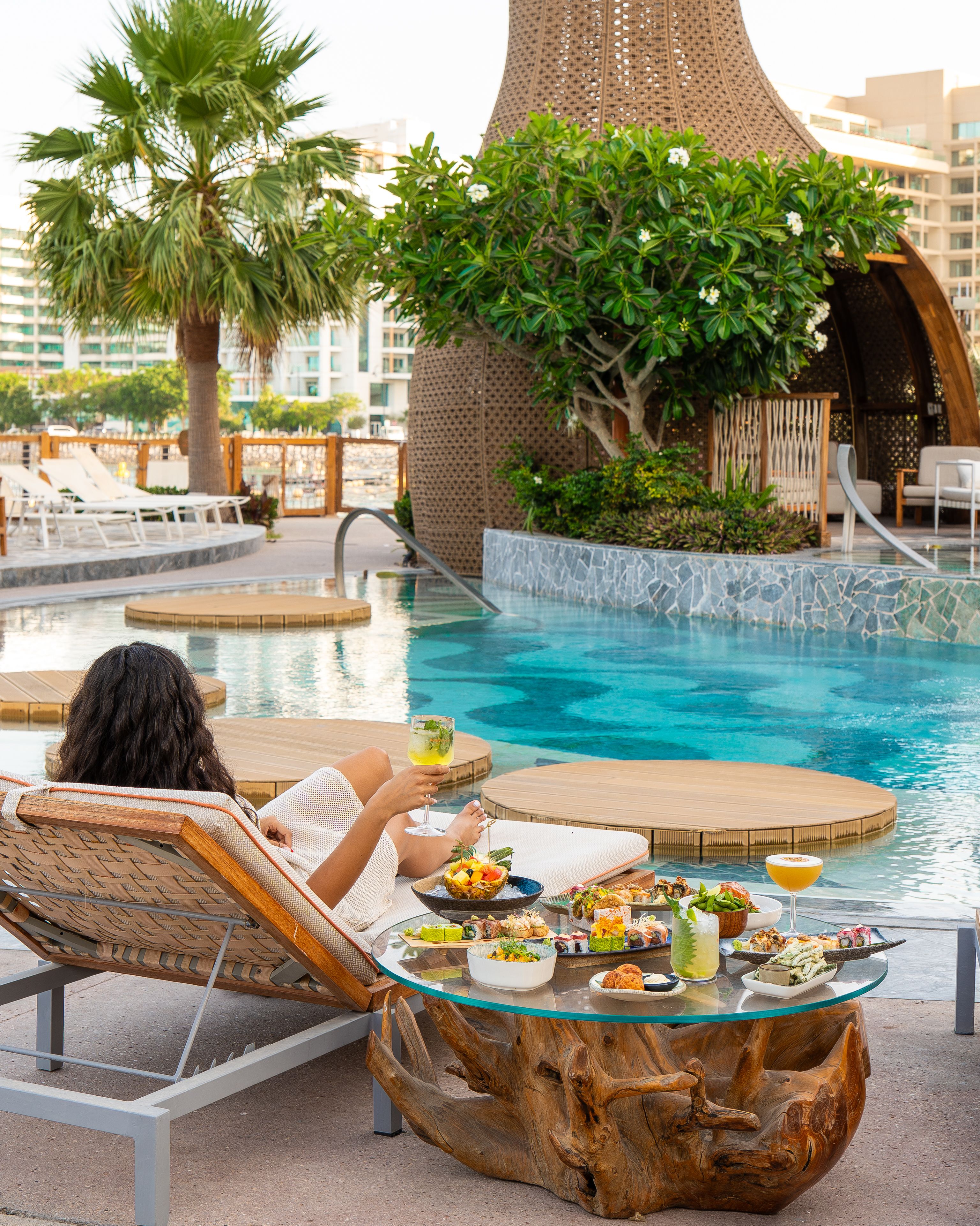 Sushisamba Doha Beach club lady on sun lounger and dishes on table