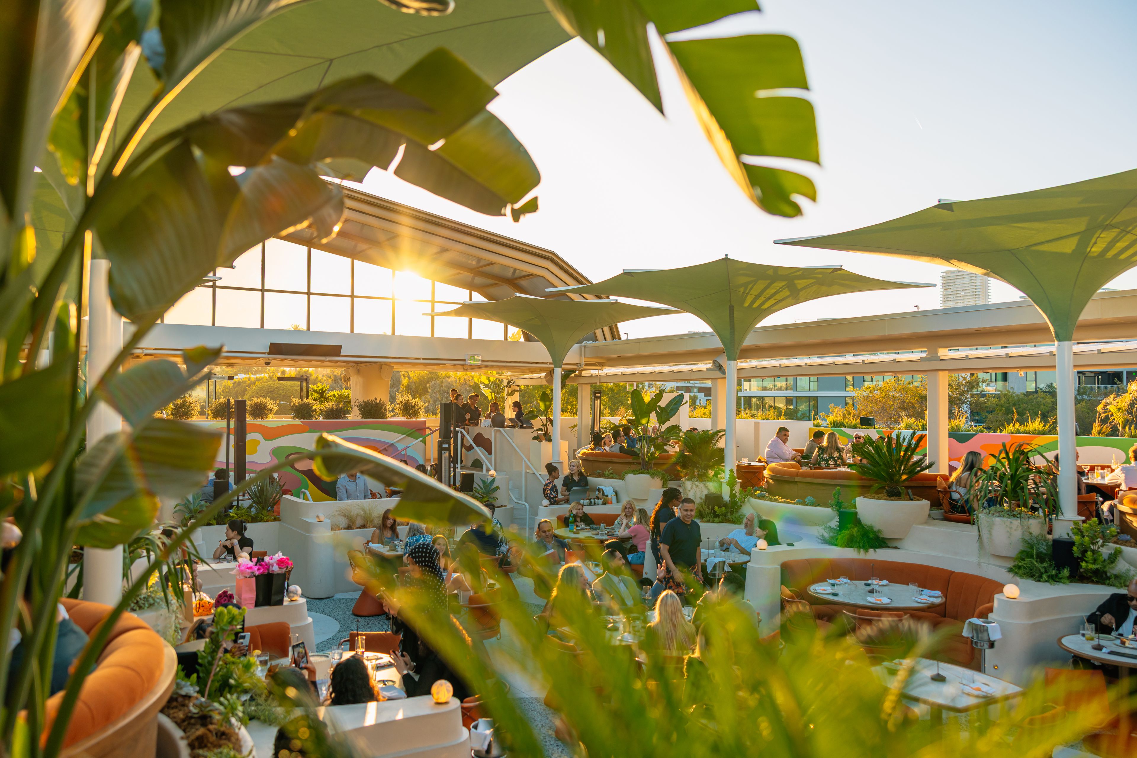 SushiSamba Los Angeles, West Hollywood rooftop restaurant, featuring lush green plants, guests enjoying lunch, and bright afternoon sunshine